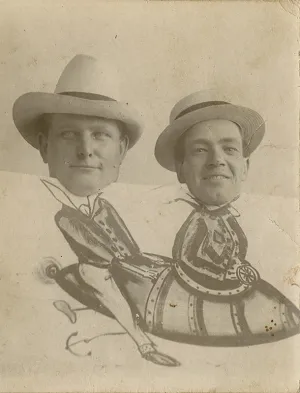 Untitled [two hat-wearing men perched behind painted panel of flying rocket]